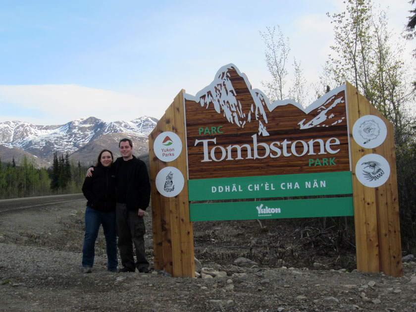 couple standing in front of a large wooden sign reading 'Tombstone Park'