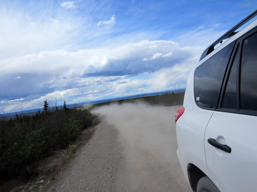 car kicking up lots of dust on a dirt road