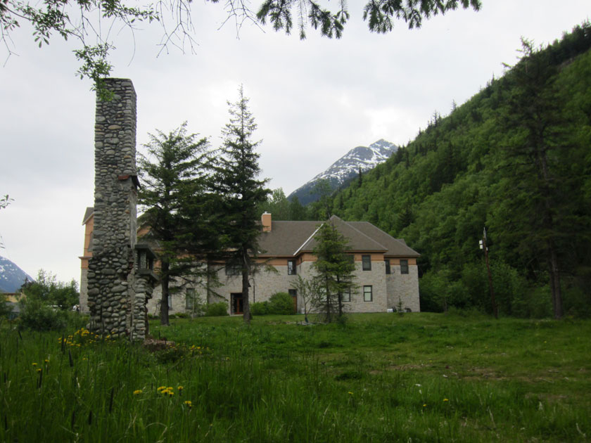 old stone chimney with a granine building behind it