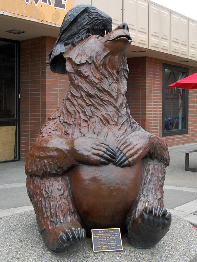 bronze statue of a bear with a raven on its head
