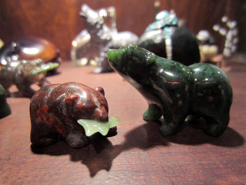 two stone bear figurines, one with a fish in its mouth and the other with its head up